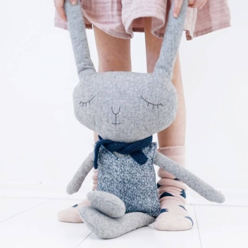 Softies Lloyd Rabbit large sitting on the floor in front of childs legs with his tweed jacket and scarf