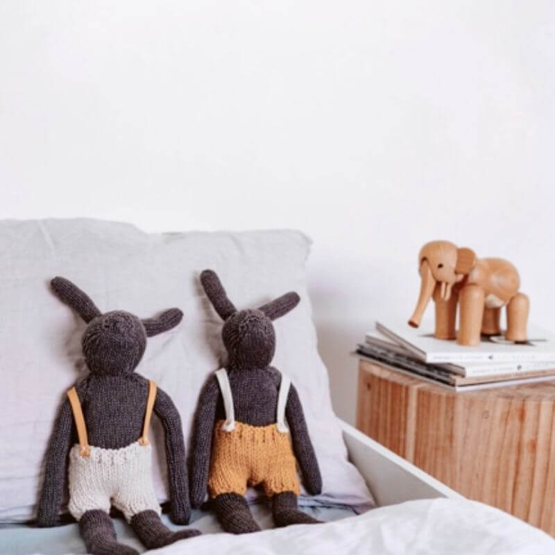 Softies Rupert and Matilda Rabbit handknitted toys sitting on a bed, both in Australian merino wool overalls
