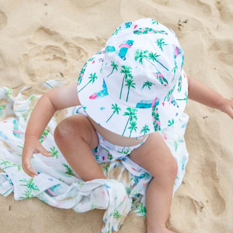Baby on the beach wearing chasing waves print swim nappy and hat