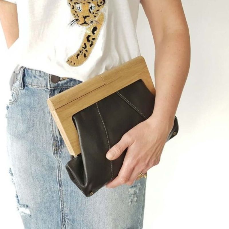 Woman holding a black leather and timber handled clutch