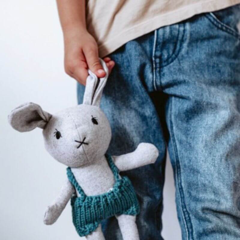 softies mini lionel rabbit in green pants dangling next to a childs leg