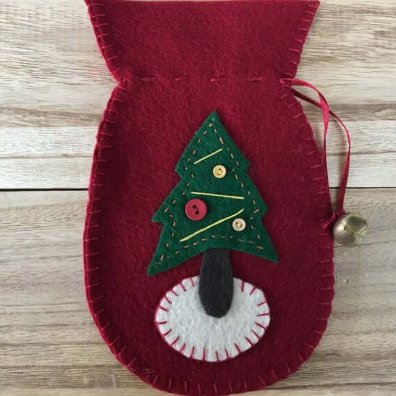 felt decoration ornament in the shape of a mitten with accented bell with a felt christmas tree on the front