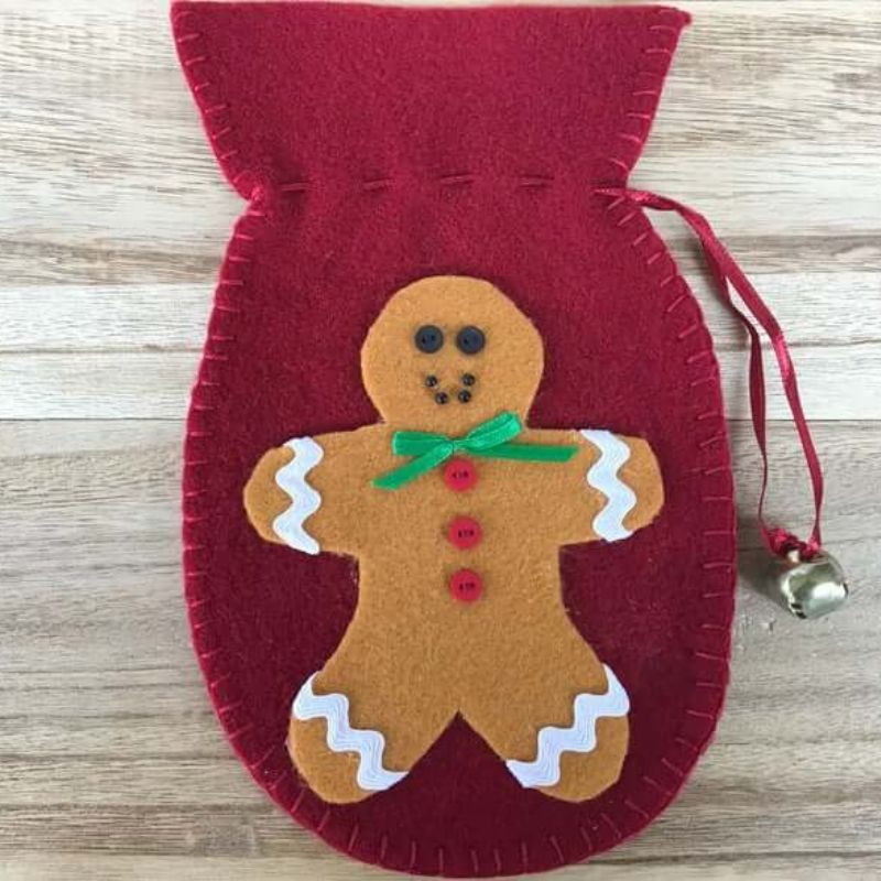 felt decoration ornament in the shape of a mitten with accented bell with a felt gingerbread man on the front