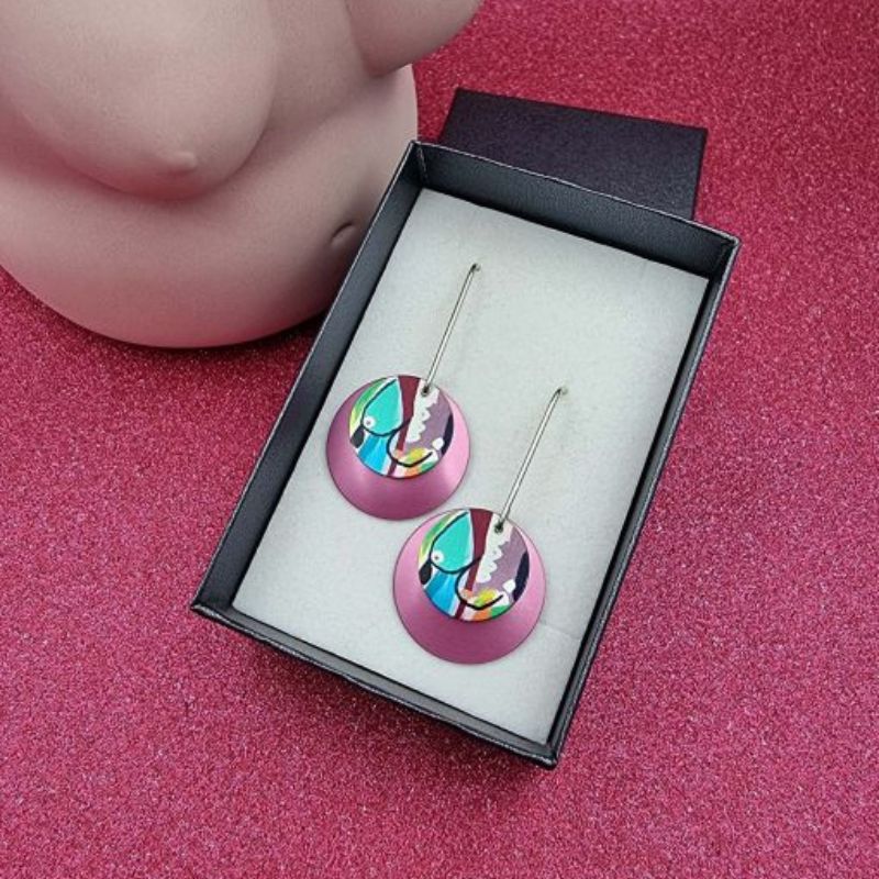 long dangle earrings with a pink disc and smaller disc of breast artwork