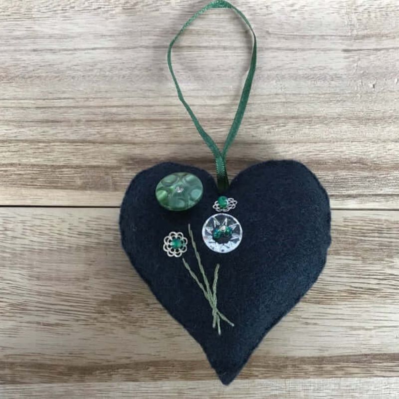 Navy felt heart with clear and green coloured buttons representing flowers and embroidery stems