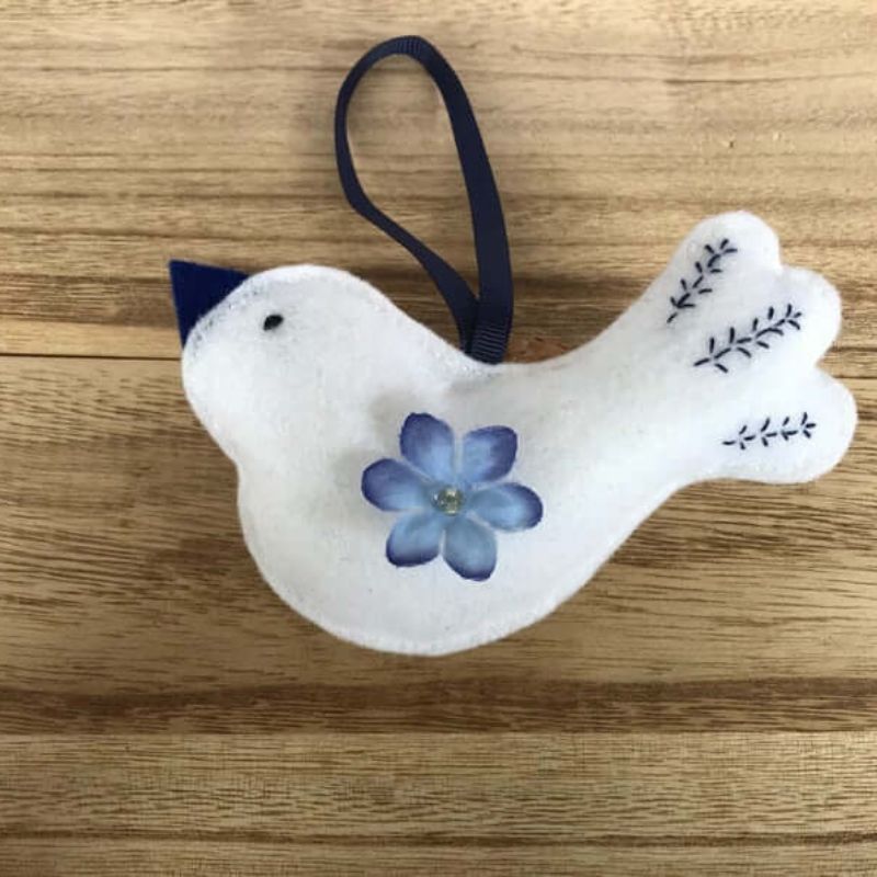 white bird ornament with blue flower and embroidery