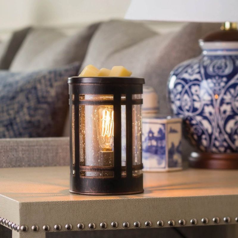 Brown metal electric candle warmer with glass inserts showing an edison bulb