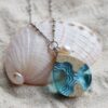 teardrop shaped necklace with pearl at the top with design of a tombolo waterway in sand and blue resin
