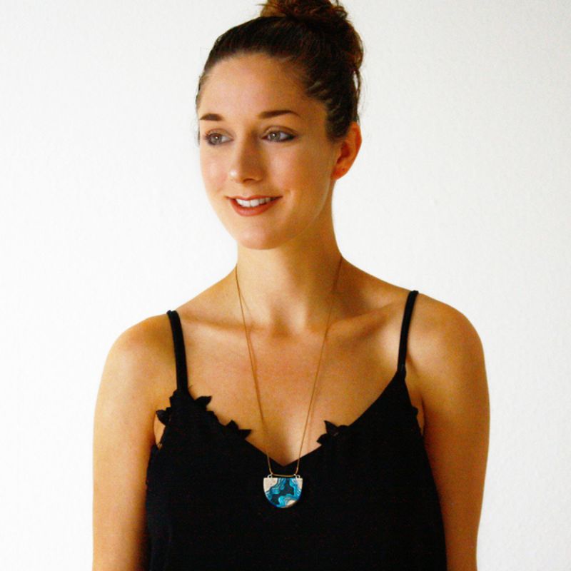 lady wearing half circle necklace in a waterway topographical design with sand and blue resin
