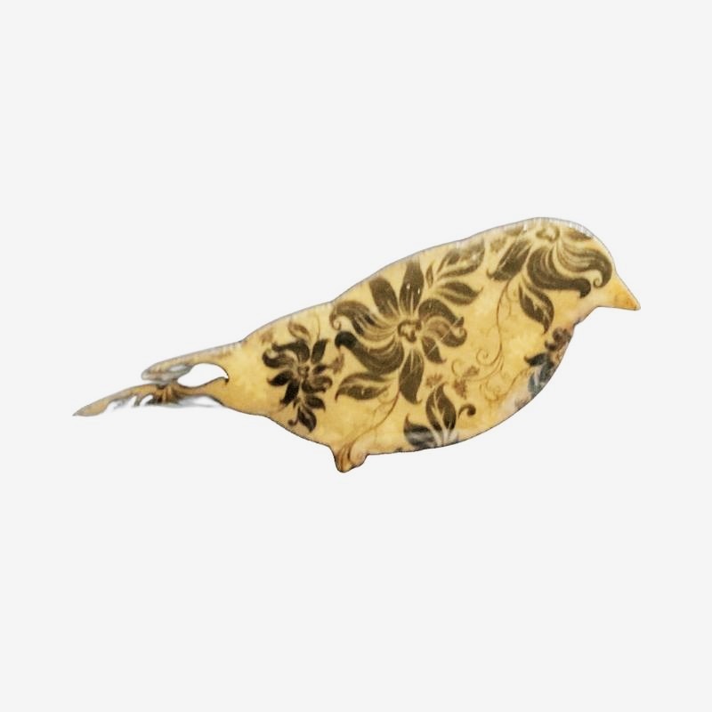 Bird design brooch with green flowers on a tan background