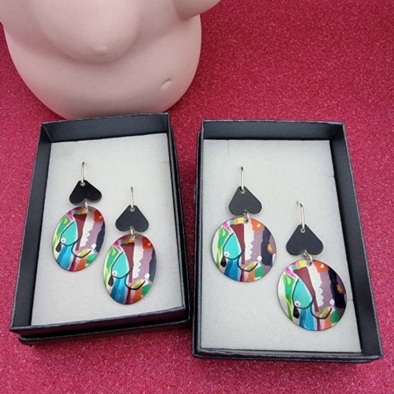 aluminium earrings with breast artwork on them with an oval disc and a round disc