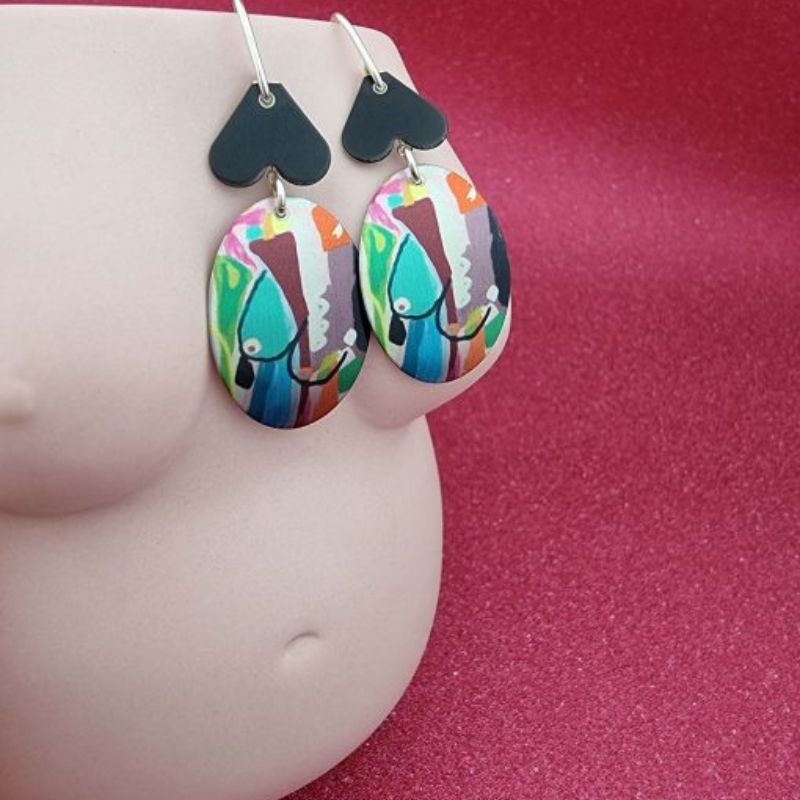 aluminium earrings with breast artwork on them with an oval disc