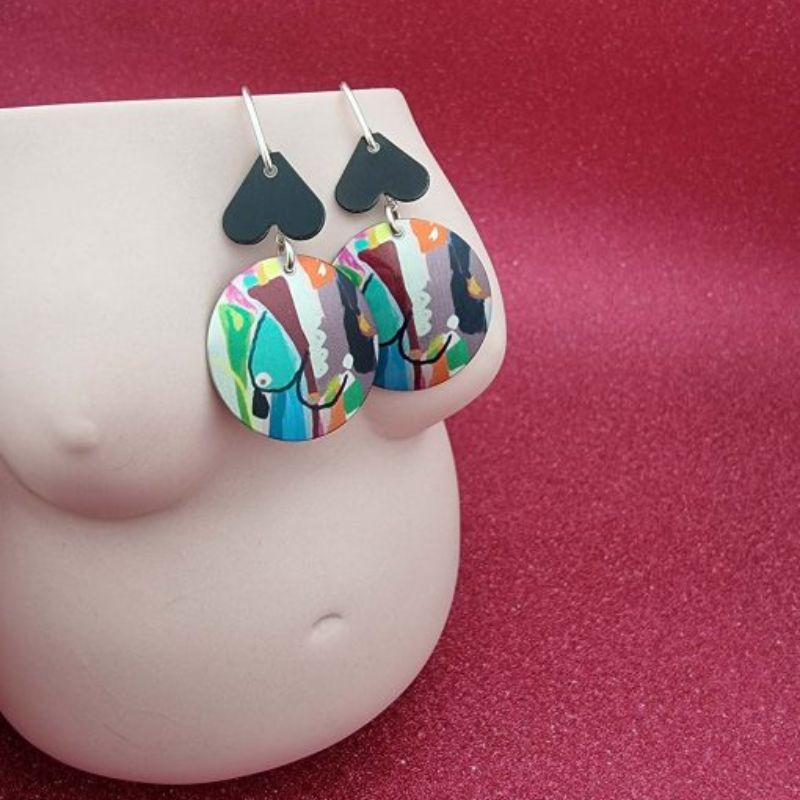 aluminium earrings with breast artwork on them with a round disc