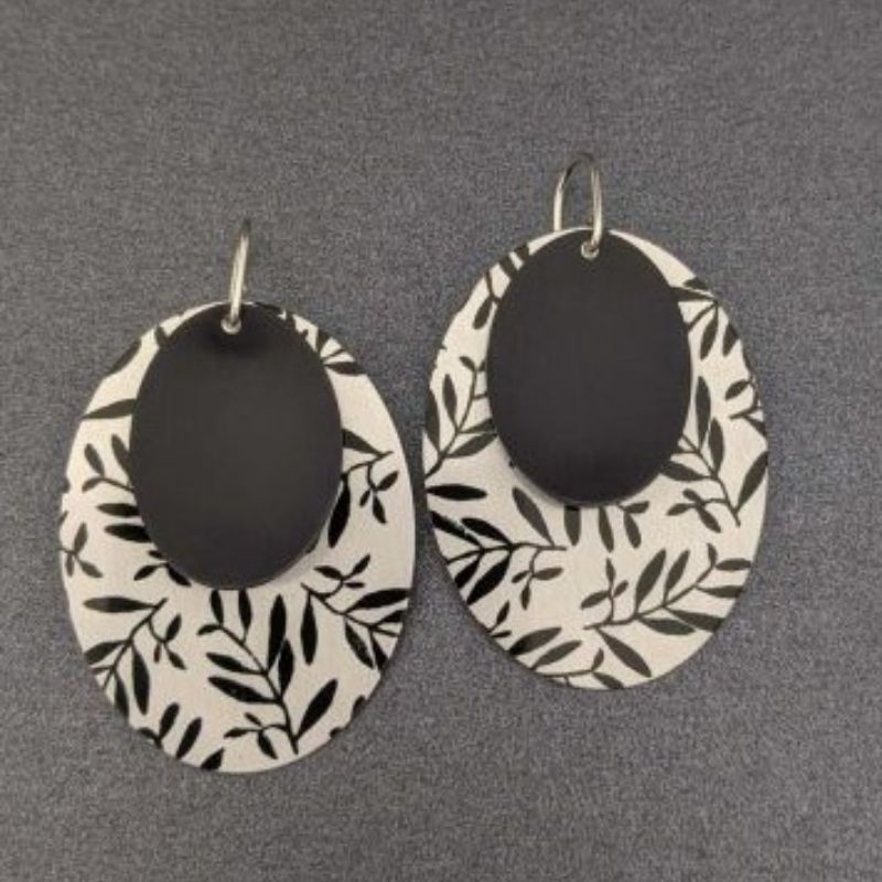 Double oval earrings with bottom disk a leaf pattern and top disc black