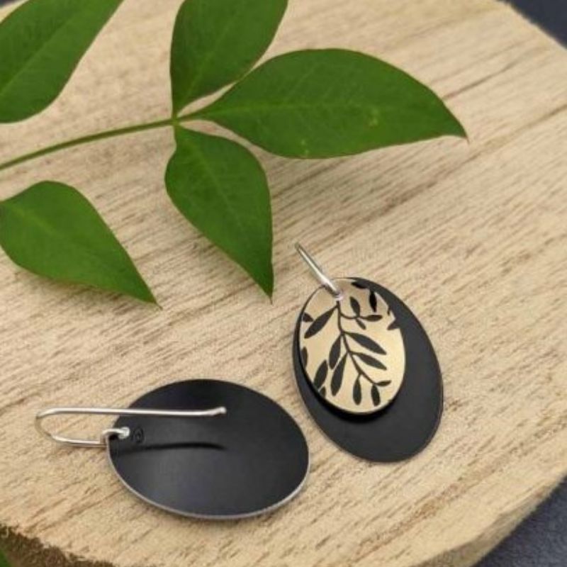 double oval earrings with gold plant print on top oval with black accent bottom oval showing back