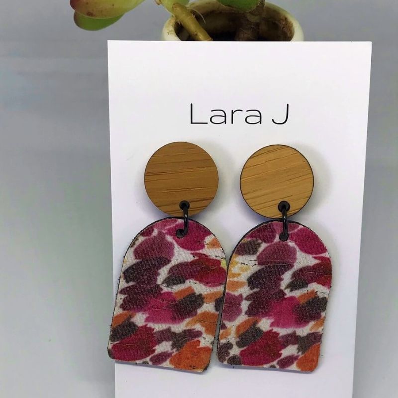 Arch shaped leather earring with red and orange splashes and bamboo tops