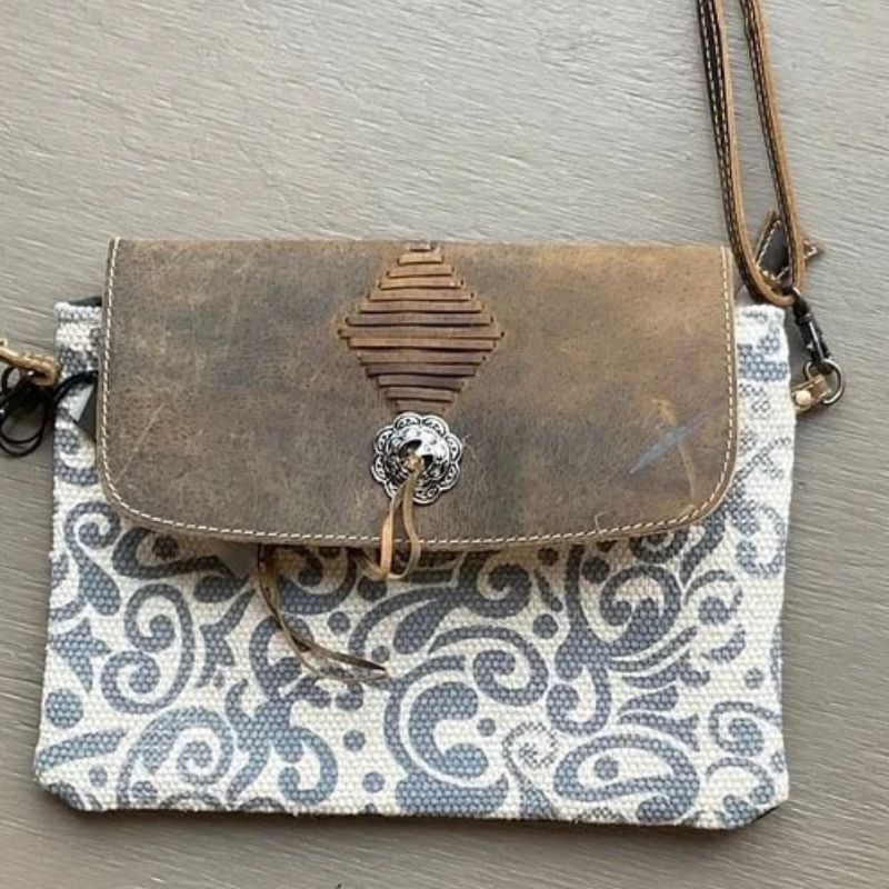 small cross body bag with swirly grey and white canvas body and leather flap with silver button and tassle