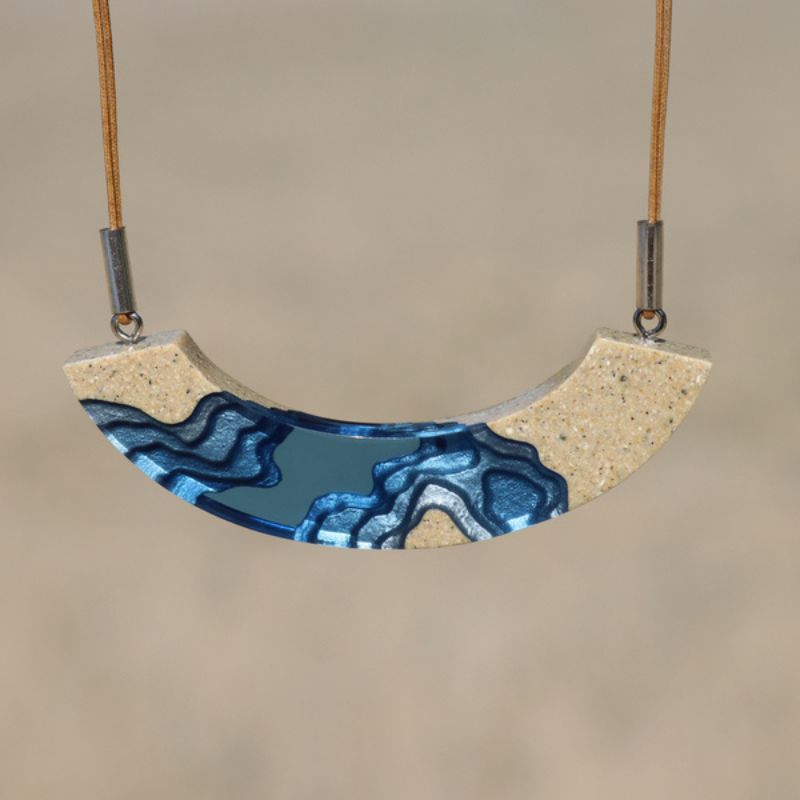 necklace in a half moon design with lagoon topographical design in sand and blue resin