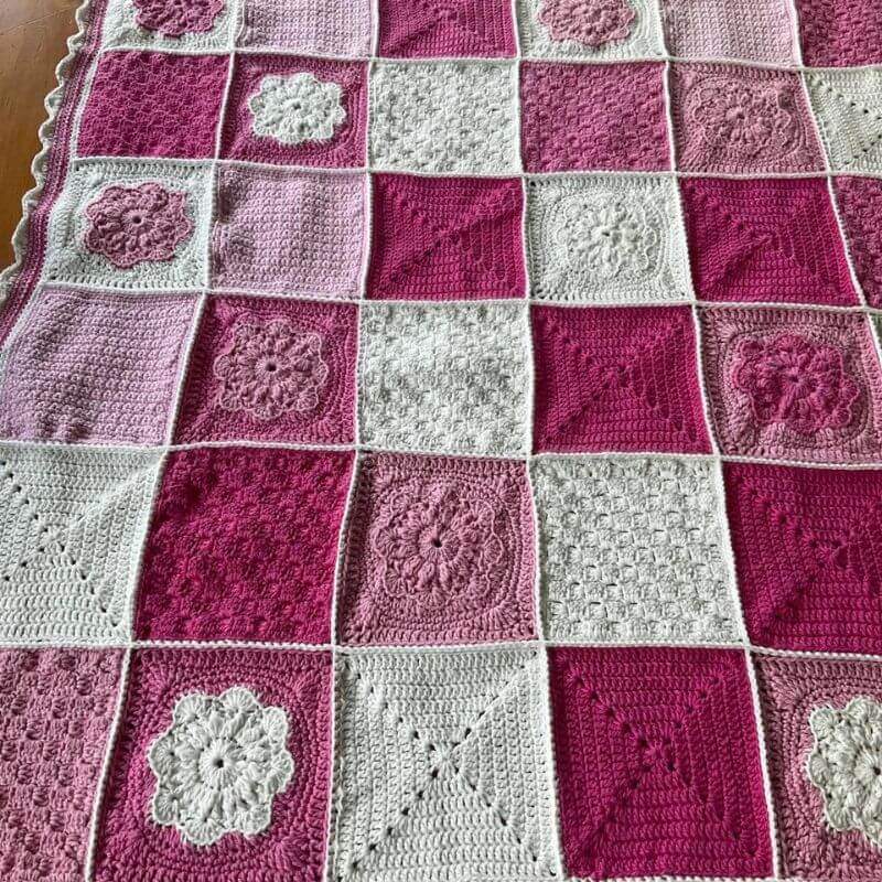 100% cotton baby blanket with textured squares of flowers and plain squares