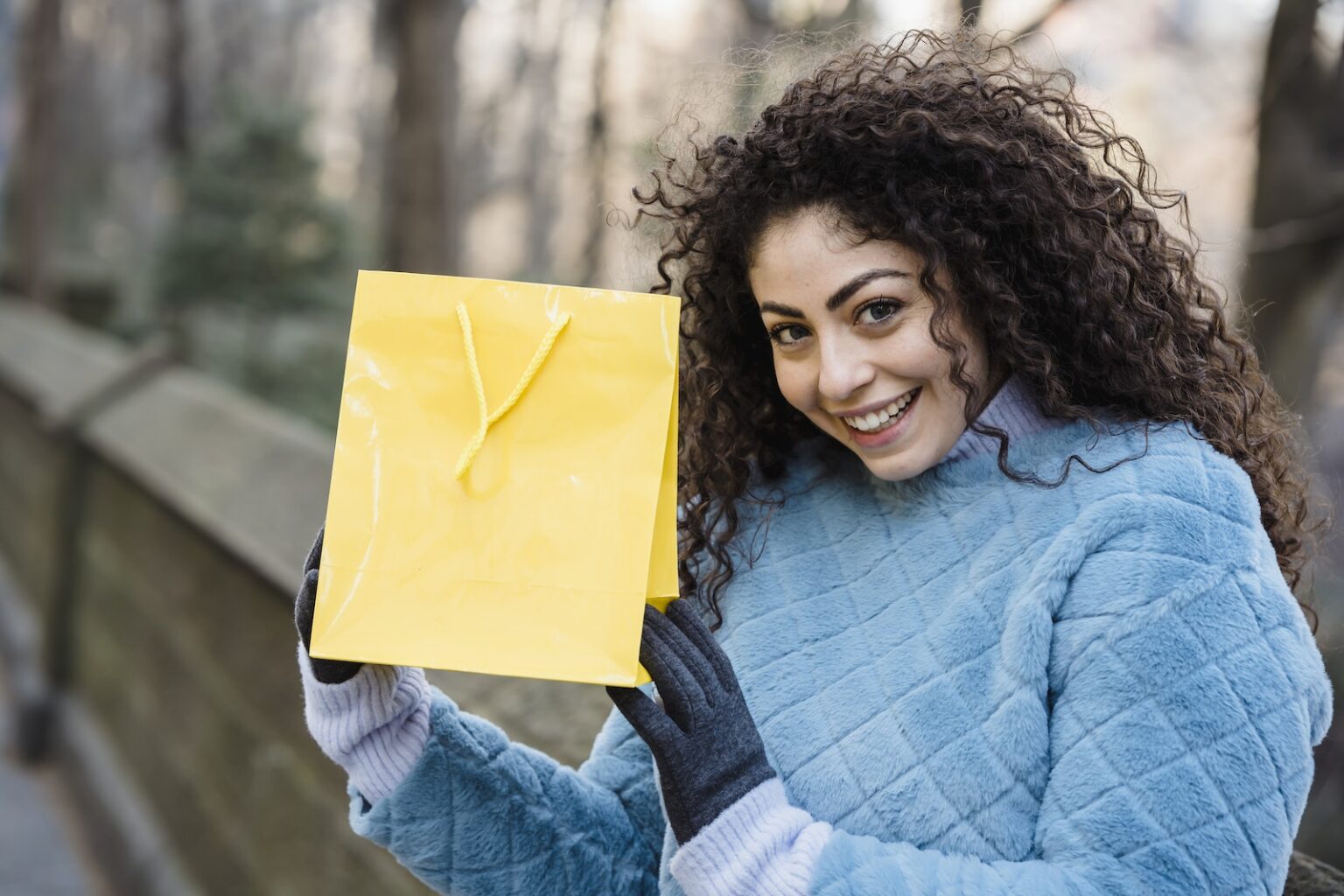 Young woman with bright yellow gift bag in hands